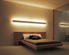 a bedroom with a bed, mirror and lights on the wall above it's headboard