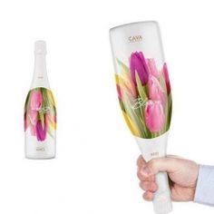 a hand holding a wine glass with pink flowers on it and a bottle in the background