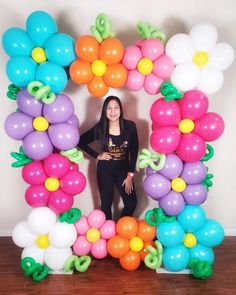 a woman standing in front of an arch made out of balloons