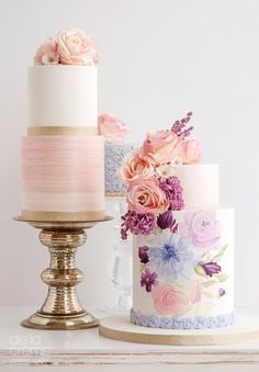 three tiered cakes with flowers on them sitting on a table next to each other