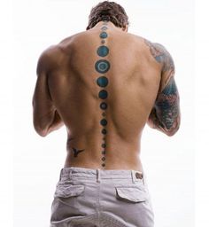 a man with his back turned to the camera and tattoos on his upper half, looking down