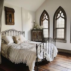 a bed sitting in a bedroom next to two windows with stained glass panes on them