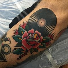 a man with a tattoo on his leg has a record and rose tattooed on it