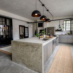 a large kitchen with an island in the middle and two lights hanging from the ceiling