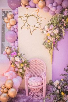 a room with balloons, flowers and a chair in front of a wall that has a sun on it