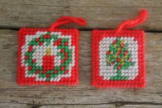 two red and white christmas ornaments hanging on wooden planks, one with a tree