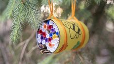 a tin can ornament hanging from a pine tree filled with colored pencils