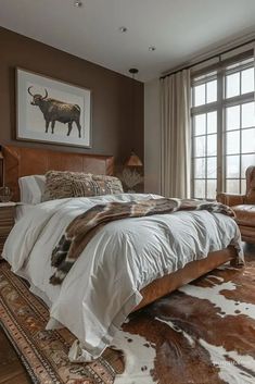 a large bed sitting next to a window on top of a wooden floor covered in cowhide