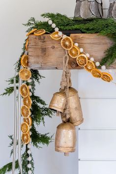 a bunch of oranges that are hanging from a wooden beam with bells attached to it