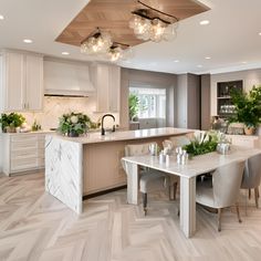 a large kitchen with an island and dining room table surrounded by chairs in the center