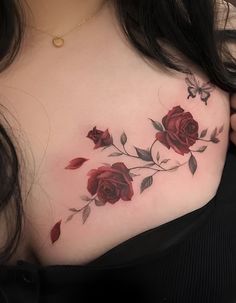 a woman's chest with red roses and leaves on her left side, while the rest of her upper body is visible