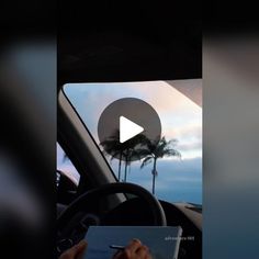 the view from inside a car looking out at palm trees and clouds in the distance