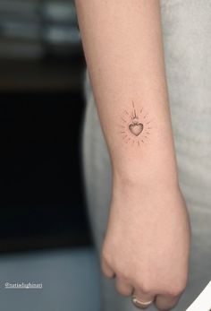 a small heart tattoo on the left wrist is shown in this image, it appears to be sunburst