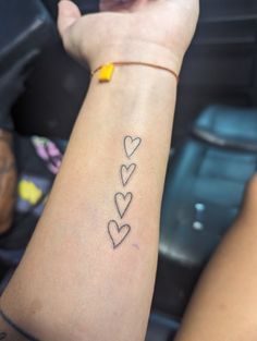 a woman's arm with three hearts tattooed on it