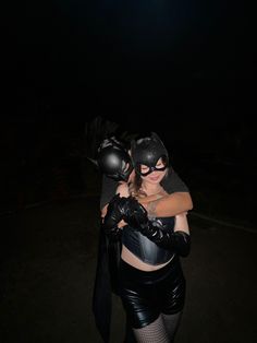 two women dressed up as batman and catwoman hugging each other in the dark at night