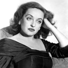 an old black and white photo of a woman with her hands on her head, posing for the camera