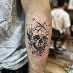 a man's arm with a skull and compass tattoo on it, in black ink