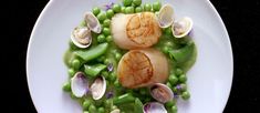 a white plate topped with peas and scallops