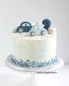 a white cake with blue frosting and cars on top