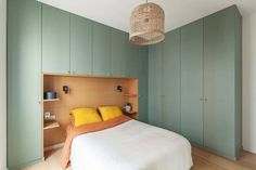 a bed sitting in a bedroom next to green cupboards