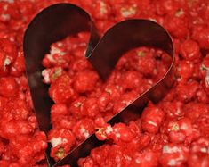 two heart shaped cookie cutters sitting in a bowl of popcorn