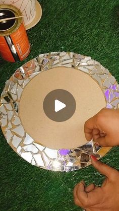 someone is making a mosaic glass plate on the grass with their fingers and thumbnails