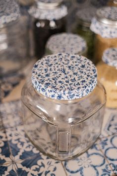 several jars with blue and white designs sit on a table top next to each other