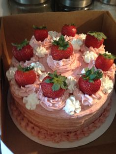 a strawberry cake in a box with white flowers and strawberries on top