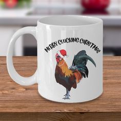 a white coffee mug with a rooster wearing a santa hat and merry clucking christmas written on it