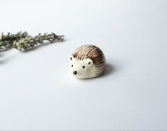 a small hedgehog figurine sitting next to a flower on a white surface