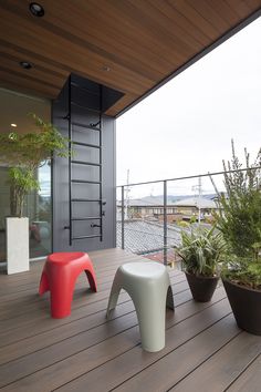 three different colored stools sitting on a wooden deck next to plants and potted plants