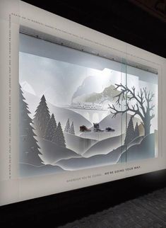 an image of a window display with trees and mountains in the background, as if it were cut out from paper