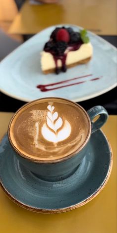 a cup of coffee sitting on top of a saucer next to a piece of cake