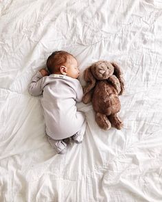 a baby laying on top of a bed next to a stuffed animal bunny rabbit toy