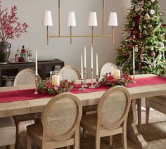 a dining room table decorated for christmas with candles and greenery on the table top