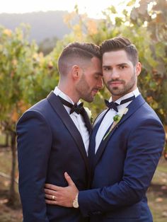 two men in tuxedos standing next to each other with their arms around each other