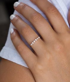 a woman's hand with a diamond ring on her left hand and white nails