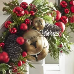 a christmas wreath with bells, pine cones and red balls hanging from the front door