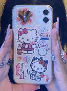 a woman holding up her phone case with hello kitty stickers on it