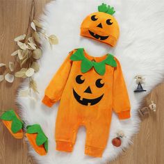 a baby's pumpkin outfit and matching hat on a white furnishing area