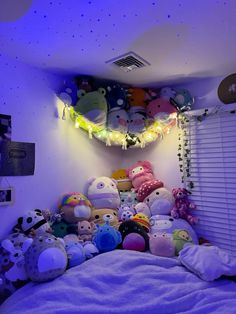 a bed with lots of stuffed animals on top of it in a room filled with lights