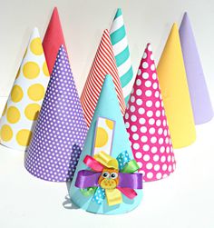 colorful party hats with polka dots and bows on them are lined up against a white wall