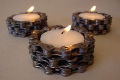 three lit candles sitting on top of a table next to each other with chains around them