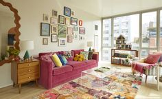 a living room filled with lots of furniture next to a window covered in framed pictures