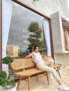 a woman sitting on a bench in front of a store window with the words it's time to make your smile alive