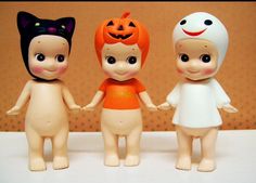 three little dolls are standing next to each other with halloween decorations on their heads and hands