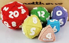 four crocheted balls with numbers on them sitting in front of a cardboard box