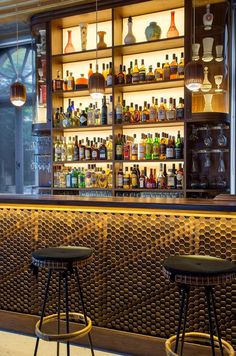 two stools in front of a bar with bottles on the shelves