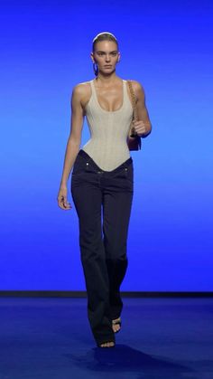 a woman walking down a runway wearing black pants