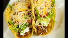 two tacos filled with meat, cheese and lettuce on a white plate